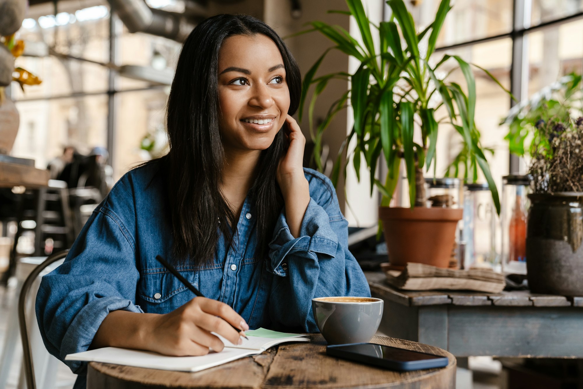 Smiling young african woman writing in notebook